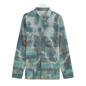 Puede incluir: Una camisa de manga larga con un patrón único. La camisa presenta un diseño tipo mosaico en tonos de verde azulado, gris y blanco. El cuello y los puños son de color blanco liso. La camisa está colgada de una percha blanca.
