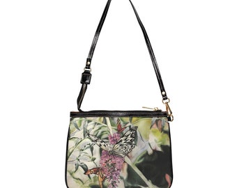 May include: A black leather shoulder bag with a zipper closure and a floral print featuring butterflies. The bag has a long adjustable strap.