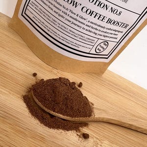 Può includere: Un sacchetto di carta marrone con un'etichetta bianca che recita "Potley's Potion No. 8: 'Flow & Glow' Coffee Booster". L'etichetta include anche un elenco di ingredienti, tra cui estratto di criniera di leone, estratto di coda di tacchino, estratto di tremella, estratto di cordyceps, estratto di reishi, estratto di chaga selvatica, estratto di ashwagandha ed estratto di rhodiola. Il sacchetto è su una superficie di legno con un cucchiaio di legno pieno di polvere marrone.