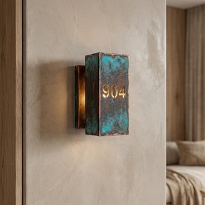 Zimmernummernschild aus patiniertem Kupfer, oxidierte Kupfer-Wandplakette mit beleuchtetem Ausschnitt „904“, rustikaler Hotel-Türbeschilderung, moderne Flurwand