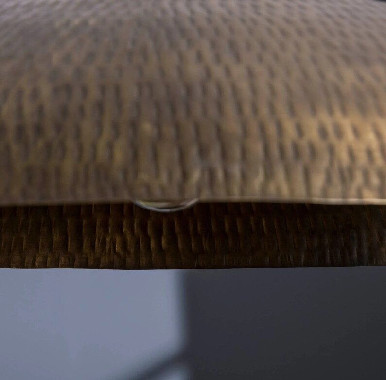 May include: A close-up of a hammered brass tray with a textured surface.