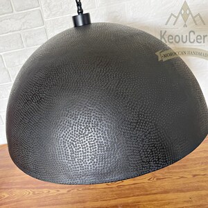May include: Black metal pendant light with a textured dome-shaped shade. The shade has a hammered finish and a small chain hanging from the top.
