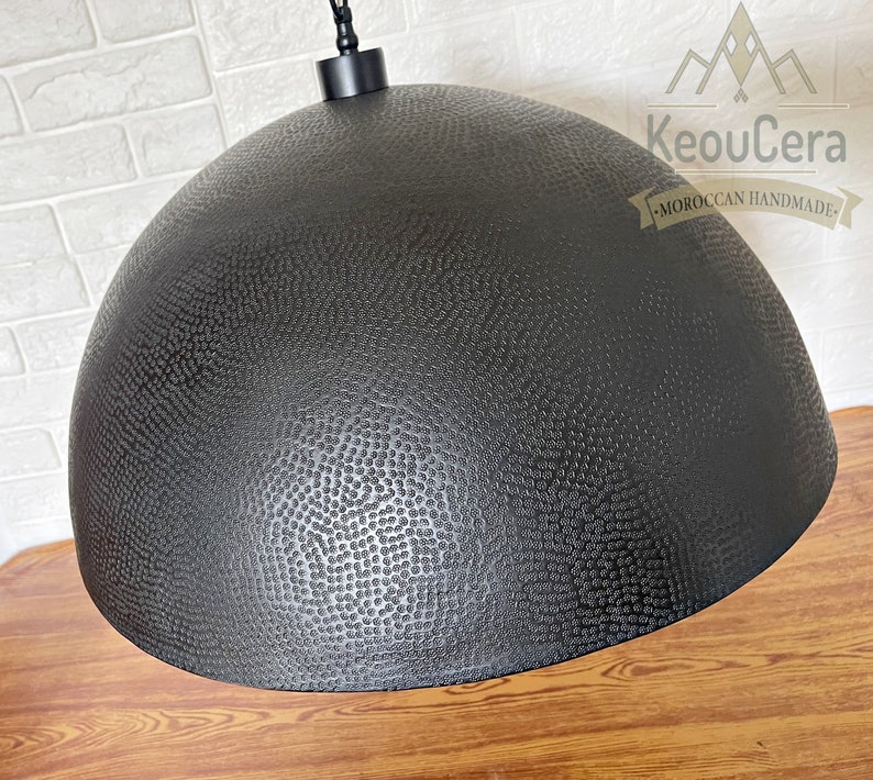 May include: Black metal pendant light with a textured dome-shaped shade. The shade has a hammered finish and a small chain hanging from the top.