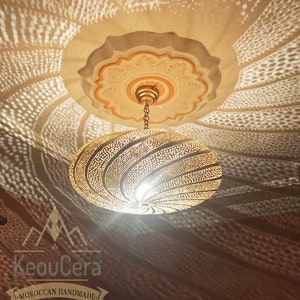 May include: A gold-toned metal ceiling light fixture with a circular, patterned shade. The light casts a geometric pattern on the ceiling.