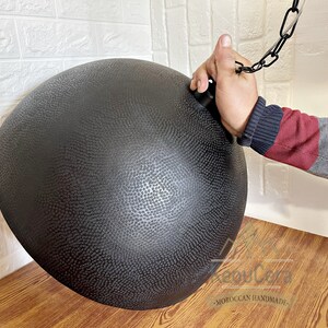 May include: Black metal pendant light fitting with a hammered texture. The light fitting is hanging from a chain.