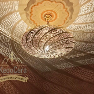 May include: A gold Moroccan pendant light with a geometric pattern. The light casts intricate shadows on the ceiling.