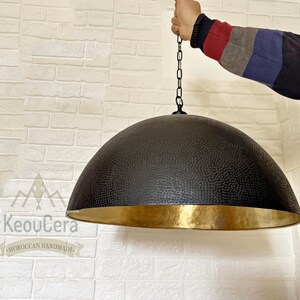 May include: A black and gold dome-shaped pendant light fixture with a textured surface. The light is hanging from a chain.