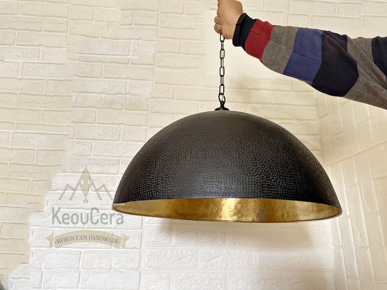May include: A black and gold dome-shaped pendant light fixture with a textured surface. The light is hanging from a chain.