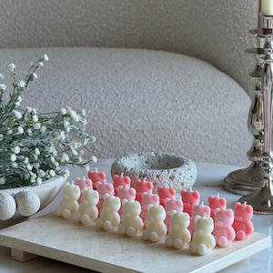 May include: A collection of small, bear-shaped candles in alternating shades of cream and soft pink, arranged in rows on a rectangular stone tray. Each candle features a simple wick at the top. The text TheFavourShopAU is visible in the bottom right.