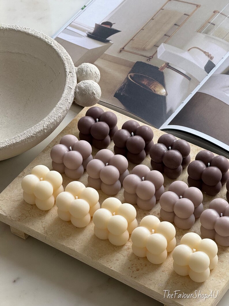May include: A selection of bubble-shaped candles in cream, pale pink, and brown hues, displayed on a rectangular stone tray. The candles feature a smooth, spherical design. The FavourShopAU is printed on the bottom right.