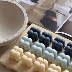May include: A selection of bubble candles in shades of cream, pale blue, and navy blue, arranged on a light-toned rectangular tray. The candles are clustered together. The FavourShopAU is printed on the bottom right corner.