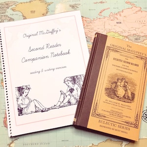 May include: A vintage, brown, hardback book titled "The Original McGuffey's Eclectic Second Reader" for younger classes in schools with engravings. The book is open to reveal the title page and a page with illustrations.  The book is next to a white notebook with a spiral binding and the title "Original McGuffey's Second Reader Companion Notebook" in purple script.