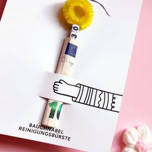May include: A white greeting card featuring a graphic of an arm holding a rolled-up ten euro banknote. The banknote is topped with white letter beads spelling 30 and a yellow fuzzy pipe cleaner. The text reads BAUCHNABEL REINIGUNGSB&Uuml;RSTE.