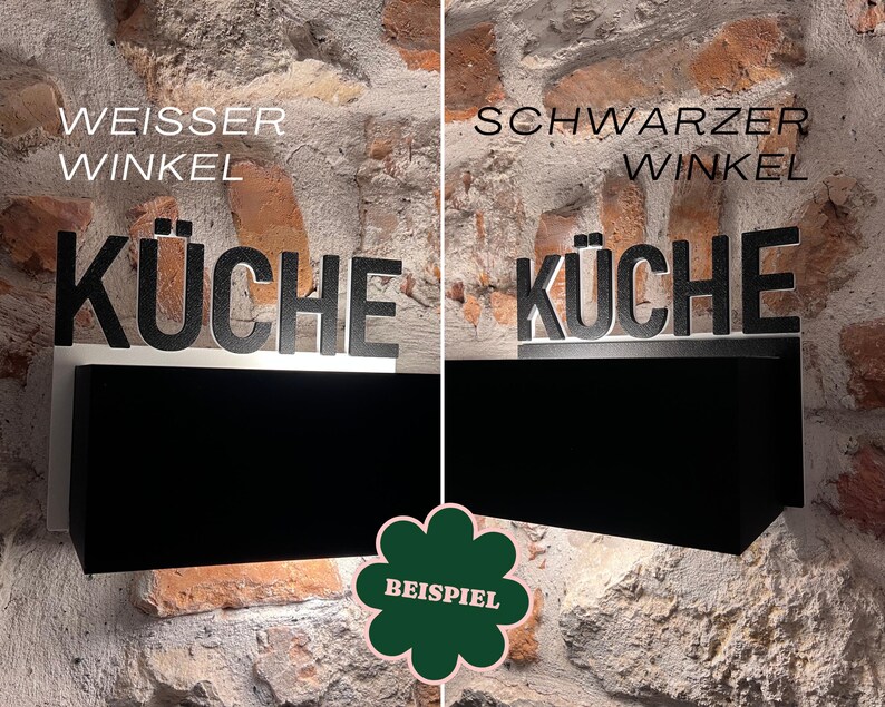 May include: A black and white kitchen sign with the word "K&Uuml;CHE" in large letters. The sign is mounted on a black rectangular base, with the text "WEISSER WINKEL" above the word "K&Uuml;CHE". The background is a brick wall.