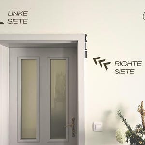 May include: A white door with two glass panels and a gold handle is centered in the image. On the wall, black text and arrows indicate directions: "LINKE SEITE" and "RICHTE SEITE". A small logo and the word "KLO" are also visible.