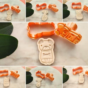 Puede incluir: Cortadores de galletas de pl&aacute;stico naranja con formas de perros, incluyendo un pug, un dachshund y un terrier. Los cortadores est&aacute;n junto a las galletas que crean, que son de color marr&oacute;n claro y presentan dise&ntilde;os detallados. La imagen es un collage de diferentes dise&ntilde;os.