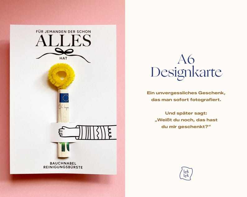 Op de afbeelding: Een witte rechthoekige kaart met de tekst F&Uuml;R JEMANDEN DER SCHON ALLES HAT en BAUCHNABEL REINIGUNGSB&Uuml;RSTE. Een gele pijpenrager is aan de kaart bevestigd, vastgehouden door een zwart-witte illustratie van een arm en een hand.