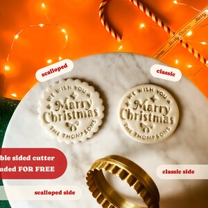 May include: A double-sided cookie cutter with a scalloped and classic design. The cutter is made of gold metal and features the text "We wish you a Merry Christmas The Thompsons".