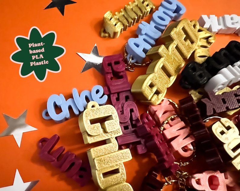 May include: A collection of personalized keychains made from plant-based PLA plastic. The keychains are in various colors, including gold, blue, red, pink, and brown. The keychains are spelled with different names, including Chloe, Anthony, Elizabeth, and Emma.