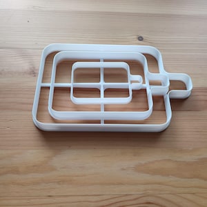 Puede incluir: Cortador de galletas de plástico blanco con cuatro formas cuadradas de diferentes tamaños. El cortador está diseñado para crear galletas en capas.