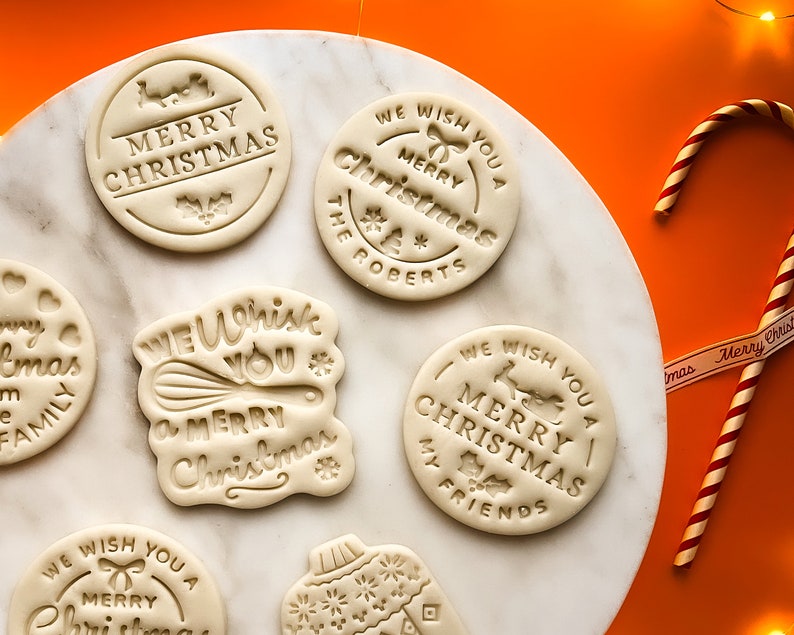 May include: A set of seven white cookie cutters with various Christmas-themed designs. The cutters feature phrases like "We Wish You a Merry Christmas" and "Merry Christmas".