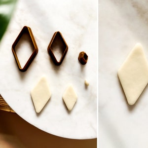 May include: A set of four diamond-shaped cookie cutters in gold metal, with two different sizes. There are also two diamond-shaped pieces of white fondant, one larger than the other.