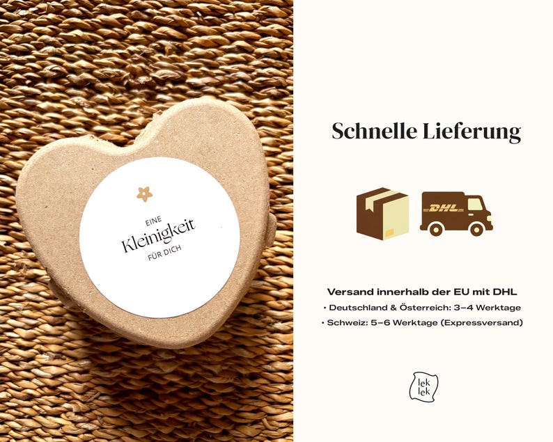 May include: A heart-shaped, light brown box with a white circular label. The label has the text "EINE Kleinigkeit F&Uuml;R DICH" in black. The box is on a woven, brown surface.