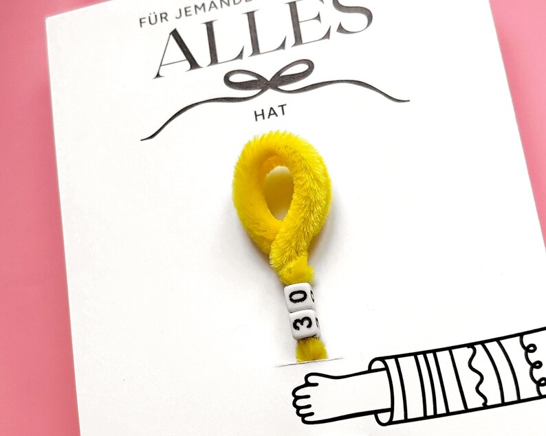 May include: A white card with the German text "F&Uuml;R JEMANDEN ALLES HAT" and a yellow question mark made of fuzzy material. The question mark has white letter beads that read "30". A cartoon hand is drawn at the bottom.