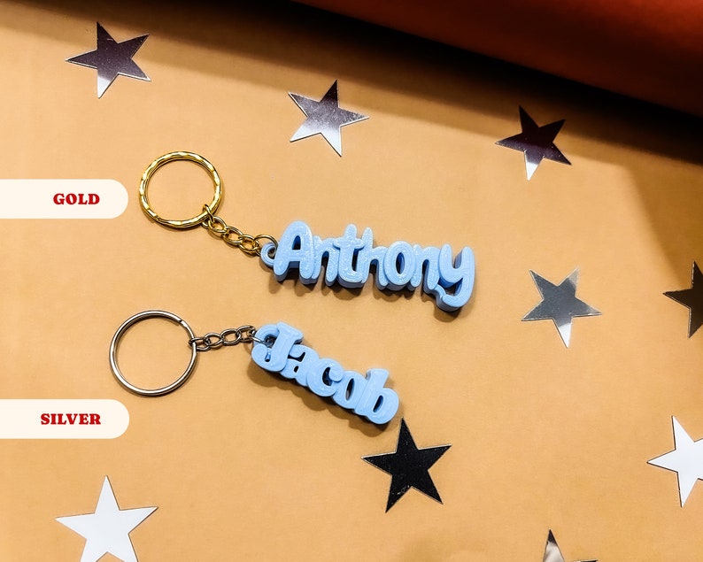 May include: Two keychains with blue plastic name tags. The keychain on the left says "Jacob" in silver and the keychain on the right says "Anthony" in gold.