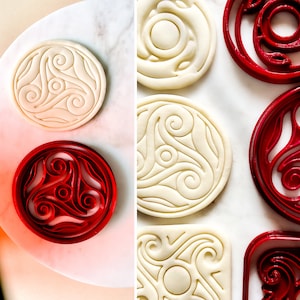Può includere: Due set di tagliapasta rotondi, un set è bianco con un design a spirale e l'altro set è rosso con un design a spirale.