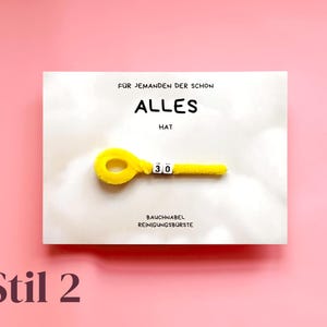 以下が含まれることがあります： ドイツ語のテキストと数字「30」が付いた黄色のモールで作られたグリーティングカード。カードには「F&Uuml;R JEMANDEN DER SCHON ALLES HAT」と「BAUCHNABEL REINIGUNGSBURSTE」と書かれています。背景はピンク色です。
