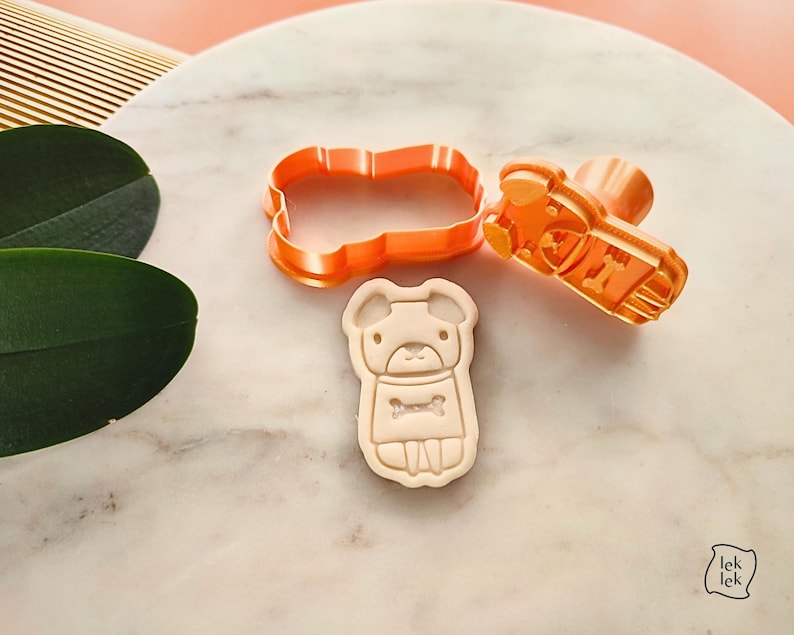 Puede incluir: Un juego de cortador y sello de galletas con forma de perro de pl&aacute;stico naranja. El juego incluye un cortador, un sello y una galleta con un dise&ntilde;o de perro y un hueso. El cortador mide aproximadamente 7,6 cm de largo.