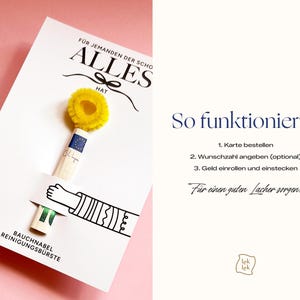 May include: A white greeting card featuring the text F&Uuml;R JEMANDEN DER SCHON ALLES HAT and a graphic of a hand holding a rolled-up banknote topped with a yellow pipe cleaner. The card includes the text BAUCHNABEL REINIGUNGSB&Uuml;RSTE and instructions for use.