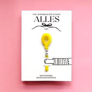 May include: A white card with the German text "F&Uuml;R JEMANDEN DER SCHON ALLES HAT" and "BAUCHNABEL REINIGUNGSB&Uuml;RSTE". The card features a yellow fluffy object with the number "30" and a cartoon hand.