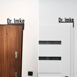 May include: Black metal sign with the text "Dr. Imke" mounted above a wooden door and a white door. The sign is in a sans-serif font. The wooden door has a dark brown frame and silver hardware. The white door has horizontal glass panels.