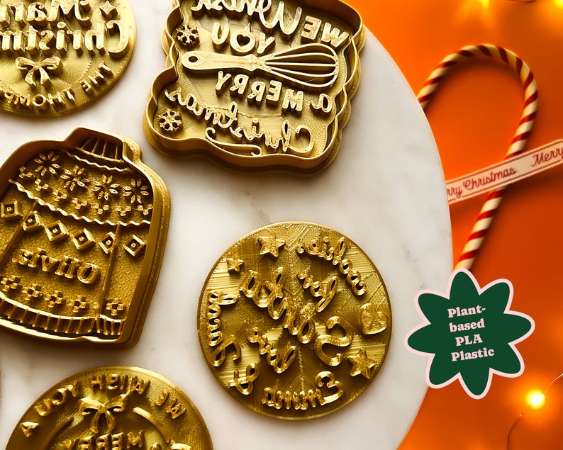 May include: A set of five gold-colored cookie cutters with Christmas-themed designs. The designs include a Christmas sweater, a Christmas tree, a candy cane, and two different Christmas greetings. The cookie cutters are made of plant-based PLA plastic.
