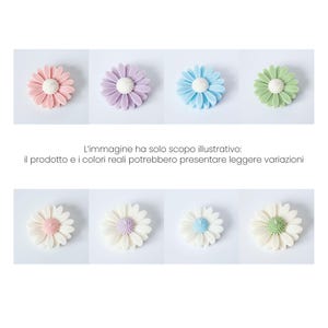 May include: An assortment of daisy-shaped decorations in various pastel colors, including pink, purple, blue, and green, with white centers. The image also includes text in Italian that states the image is for illustrative purposes only.