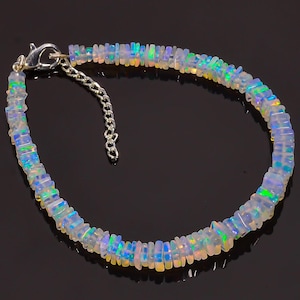 Puede incluir: Un brazalete de opalo blanco con cierre de plata. El brazalete está hecho de pequeñas cuentas de opalo de forma rectangular.