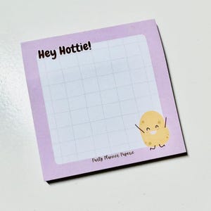May include: Purple notepad with a grid pattern and the text "Hey Hottie!" at the top. The bottom of the notepad has the text "Party Planner Paperie" and a cartoon potato with a smiling face.