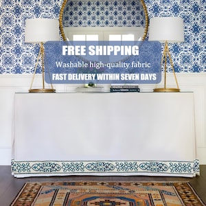 May include: A white console table with a decorative blue and white patterned border. The table is in front of a blue and white patterned wall. The text on the image says "Washable high-quality fabric".