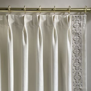 Puede incluir: Cortinas blancas con un borde de patr&oacute;n geom&eacute;trico que cuelgan de una barra de cortina dorada.