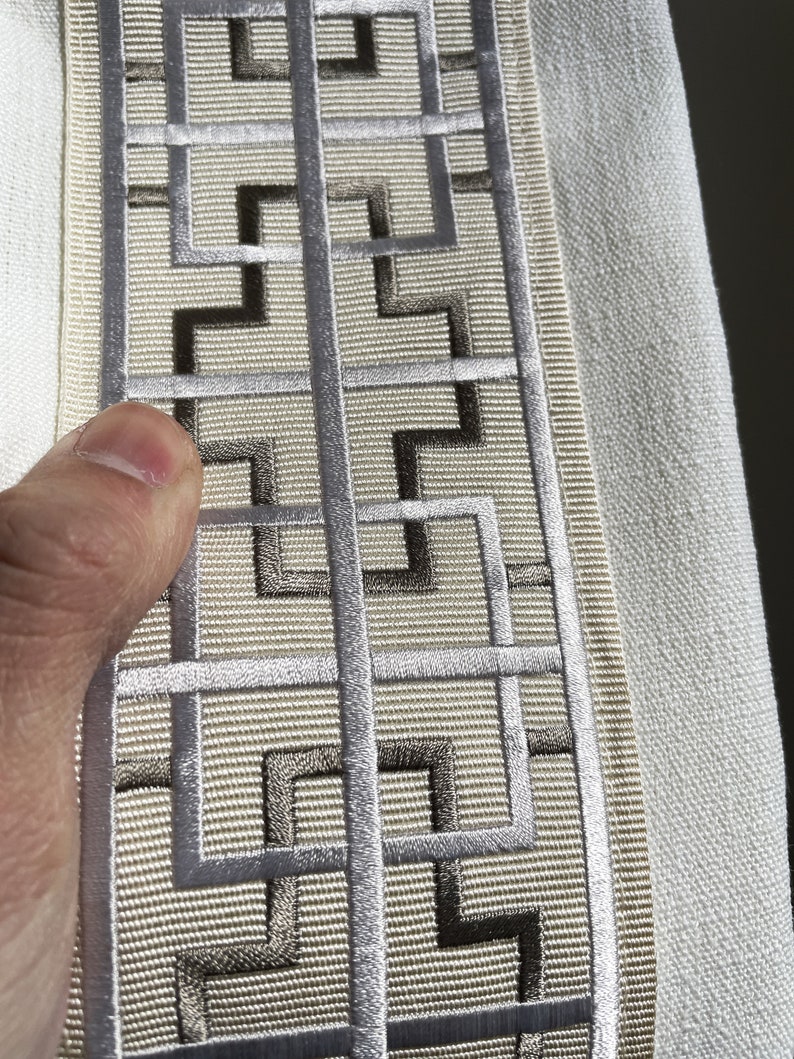 Puede incluir: Borde de tela beige con un patr&oacute;n geom&eacute;trico plateado y marr&oacute;n. El patr&oacute;n es un dise&ntilde;o repetitivo de cuadrados y rect&aacute;ngulos.