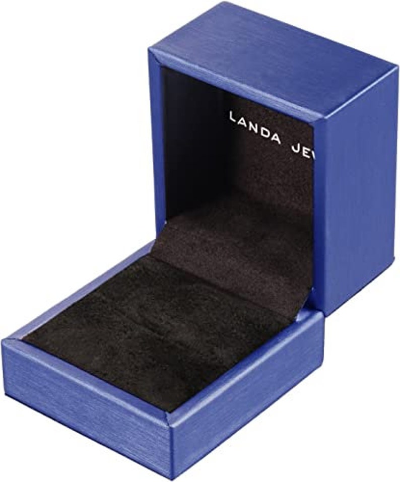 Puede incluir: Una caja de anillo de terciopelo azul con un interior de terciopelo negro. La caja est&aacute; abierta y la tapa est&aacute; levantada. La tapa tiene el texto "Landa Jew" impreso.