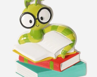 Op de afbeelding: Een groene en gele cartoonrups met een bril, bovenop een stapel van drie kleurrijke boeken. Het bovenste boek is open, met lege witte pagina's. De boeken zijn rood, geel en blauwgroen.
