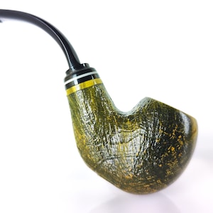 May include: A handcrafted tobacco pipe with a curved, black stem and a textured, olive green bowl. The bowl has a yellow and white band near the stem. The pipe is set against a white background.