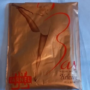 Op de afbeelding: Een verzegelde verpakking met vintage nylon kousen. De verpakking heeft een metallic gouden kleur met een rode afbeelding van een vrouwenbeen en het woord "Bas" in rode letters. De merknaam "Farnel" is zichtbaar.
