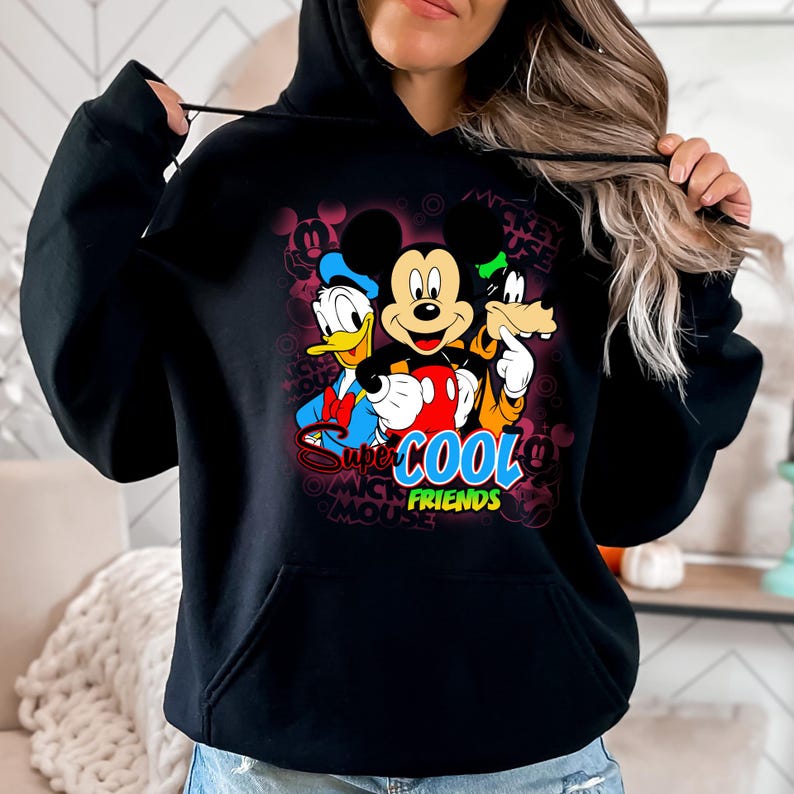 Puede incluir: Sudadera con capucha negra con un gr&aacute;fico colorido de Mickey Mouse, el Pato Donald y Goofy. El dise&ntilde;o incluye el texto "Super Cool Friends". La sudadera tiene un bolsillo delantero y una capucha con cord&oacute;n.
