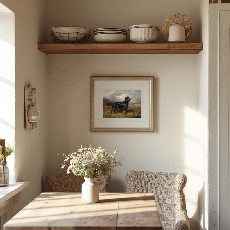 May include: A dining room scene featuring a wooden table, two woven chairs, and a framed dog painting. A shelf above holds bowls, plates, and a teapot. A vase of flowers sits on the table, bathed in sunlight.