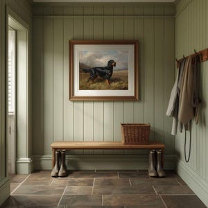 May include: A rustic entryway with sage green paneling, a wooden bench, and a framed dog painting. A woven basket sits on the bench, and a pair of boots are placed beneath it. Coats and a leash hang on a wooden rack on the wall.