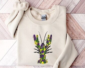 May include: A beige sweatshirt with a purple, green, and yellow splatter paint design of a crawfish.